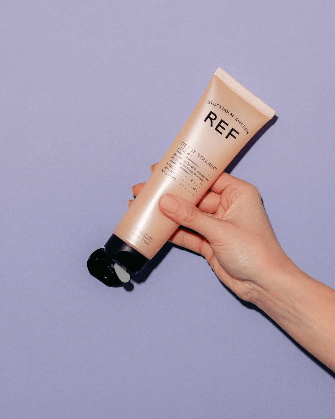 Official REF lifestyle/in-use photo (hand holding the REF Stockholm 'Get It Straight N°241' tube against a lilac background) — same REF asset filename/hash used on REF's own CDN, re-hosted as a static image by authorized Swedish REF distributor Salong Härklippet.