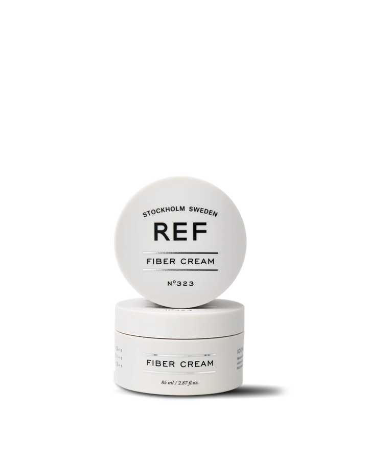 Official REF Stockholm front/hero product shot of Fiber Cream N°323 (85ml) — open jar with lid propped on top of the closed jar, showing the 'REF FIBER CREAM N°323' label. Source: refstockholm.com official product page (main slider image).