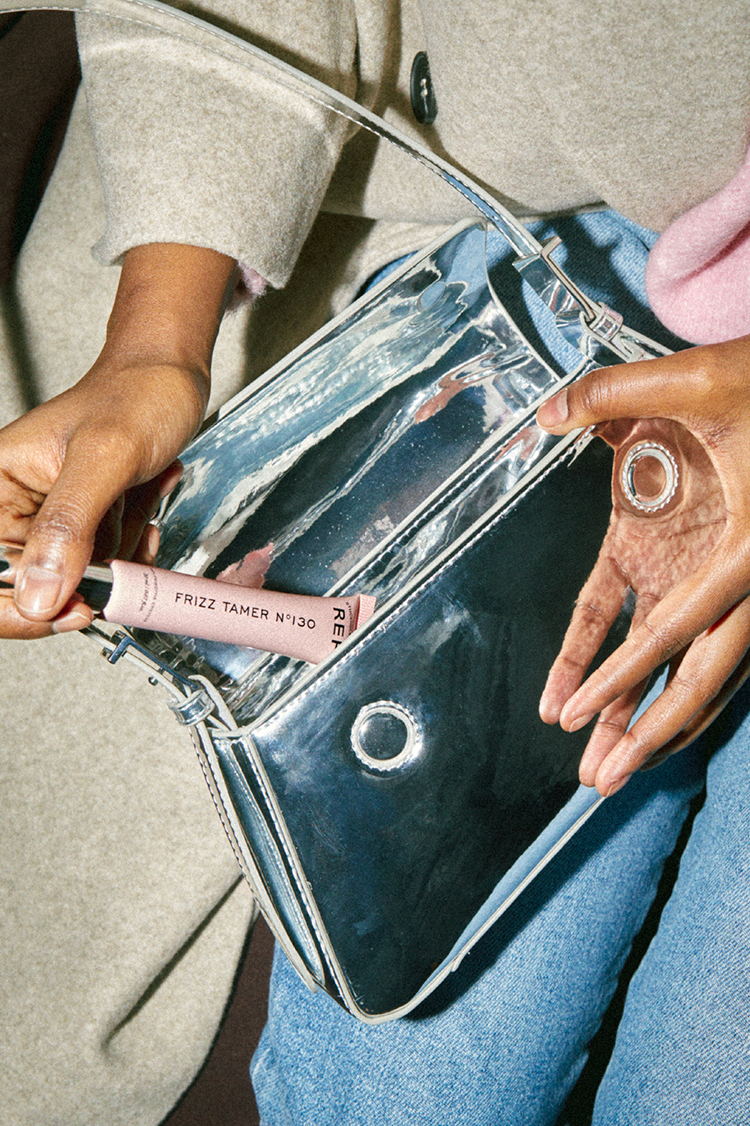 Lifestyle photo from refstockholm.com showing the pocket-sized Frizz Tamer N°130 tube being pulled from a handbag.